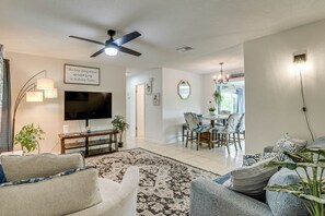 A living room with a flat-screen TV, a ceiling fan, and a dining area with a table and chairs. - Port Charlotte Home w/ Sunroom, Grill & Fire Pit! (Port Charlotte)