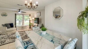 A dining area with a marble table, a ceiling fan, and a chandelier.