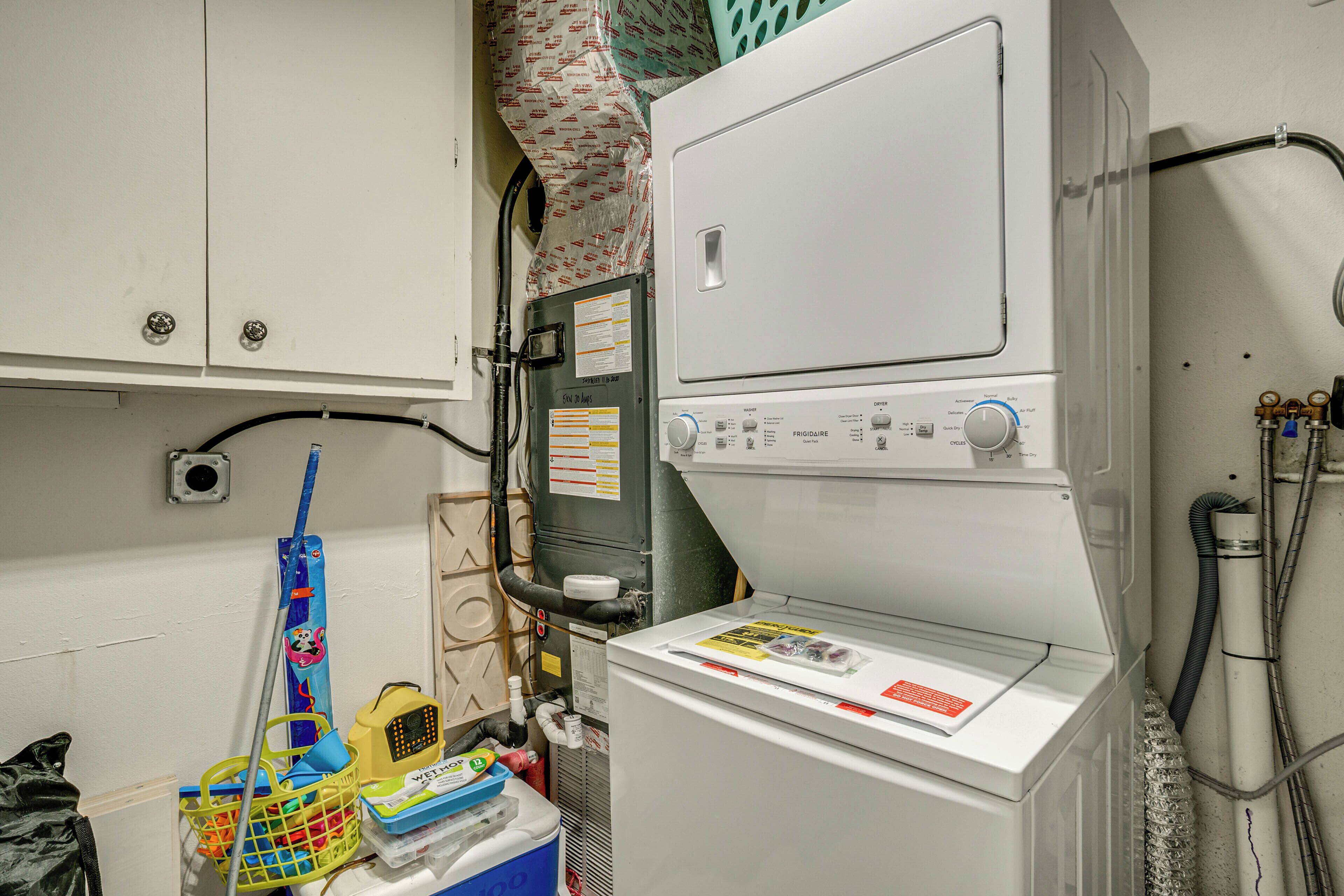 A laundry area with a washing machine, a dryer, and a utility room with various appliances and tools.