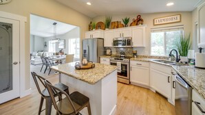 A spacious kitchen with white cabinets, granite countertops, and a farmhouse sign. - Coeur D'alene Vacation Rental ~ 4 Mi to the Lake! (Coeur d'Alene)