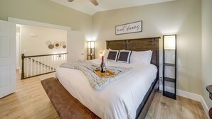 A bedroom with a large bed, a ceiling fan, a bedside table with a lamp, and a wall-mounted shelf. - Coeur D'alene Vacation Rental ~ 4 Mi to the Lake! (Coeur d'Alene)