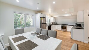 A modern kitchen with white cabinets, stainless steel appliances, and a dining area with a table and chairs.