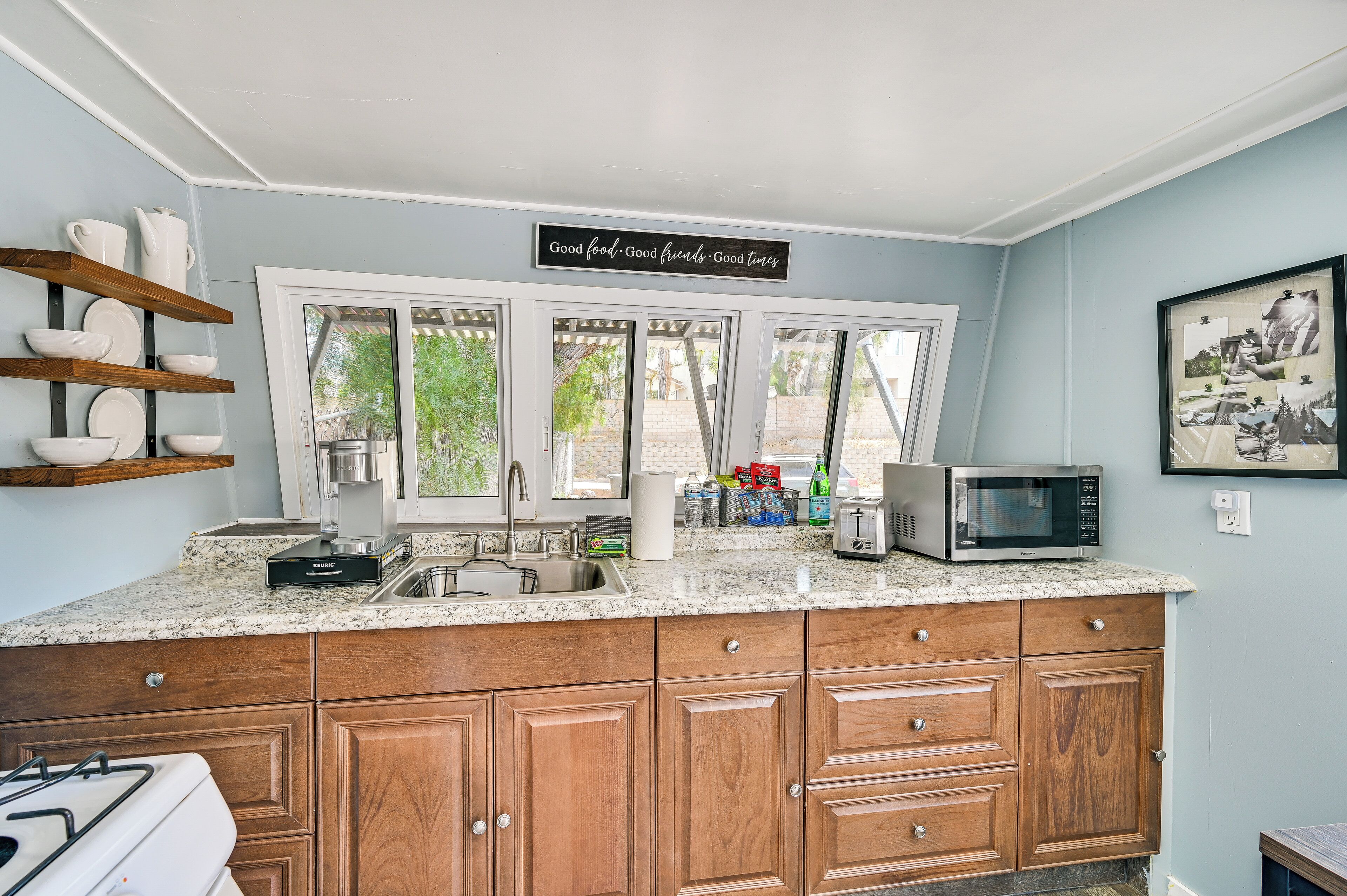 A kitchen with wooden cabinets, a granite countertop, a microwave, and a coffee maker.