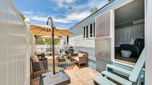 En overdækket terrasse med udendørs møbler, grill og springvand.