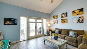 Un salon avec un mur bleu, un canapé marron, une table basse et une porte à panneaux de verre.