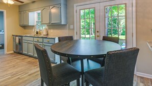 A kitchen with a round table and four chairs, light blue cabinets, and a view through a glass door. - Cozy High Point Vacation Rental: Near HPU Campus (High Point)