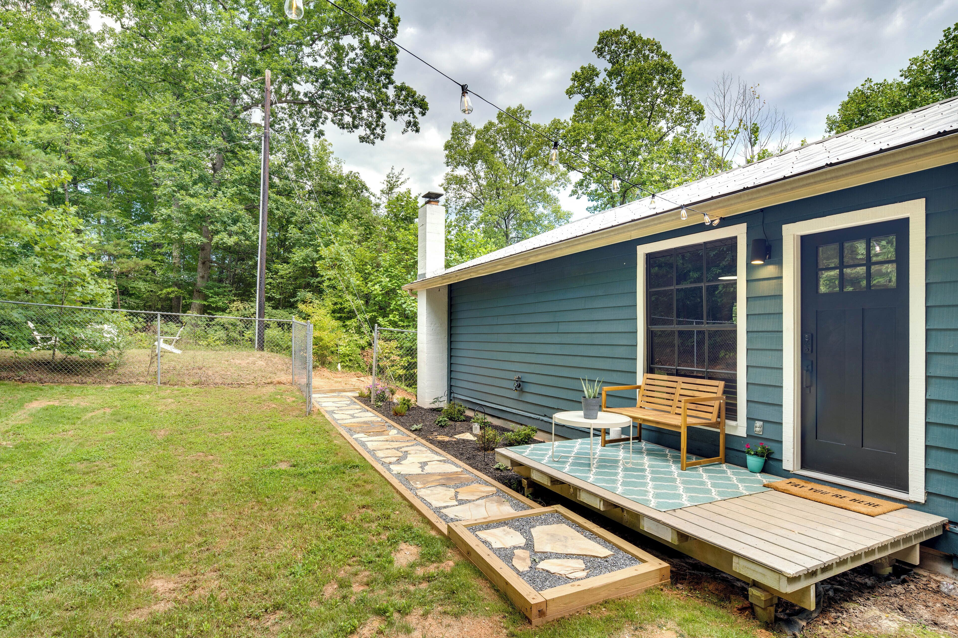 A small house with a porch, a bench, and a pathway leading to the door.