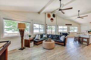A spacious living area with a leather sofa, a coffee table, and a dining area with stools.