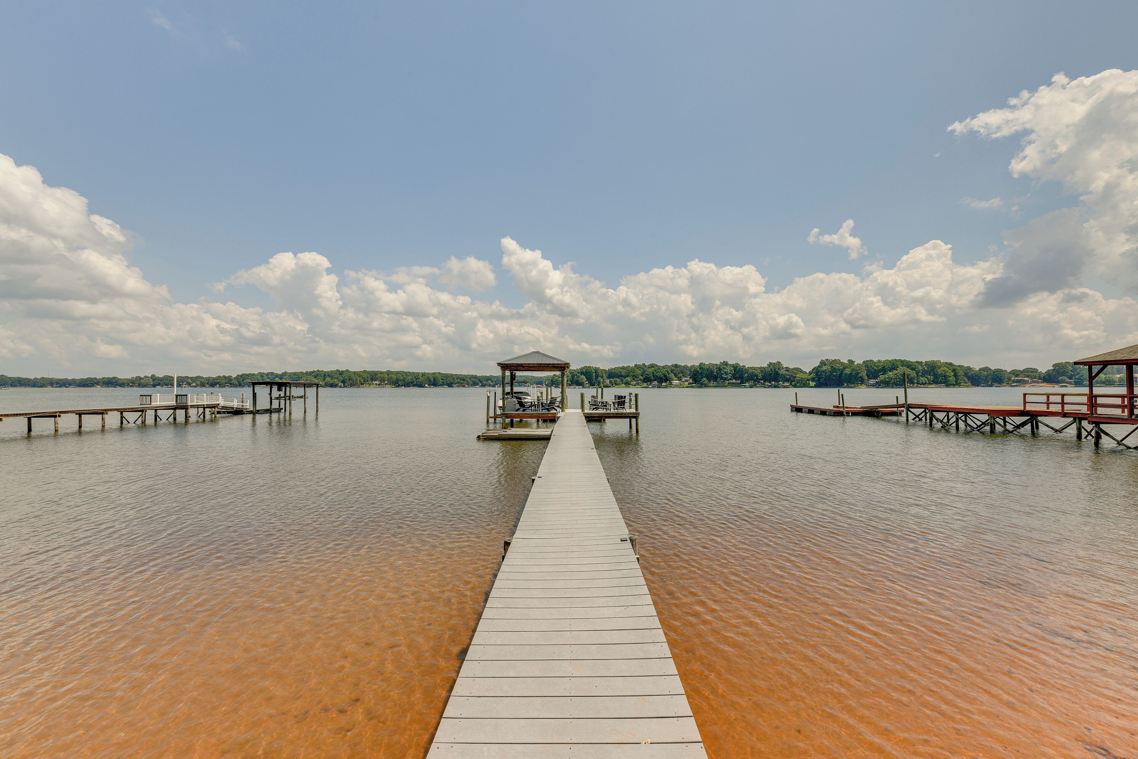 A wooden pier extending into a calm body of water with two small gazebos at the end.