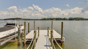 Une jetée en bois s’étendant sur une étendue d’eau calme, avec un bateau amarré sur la gauche.