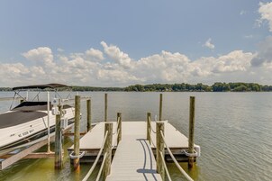 A wooden dock extending into calm water with a boat docked on the left.