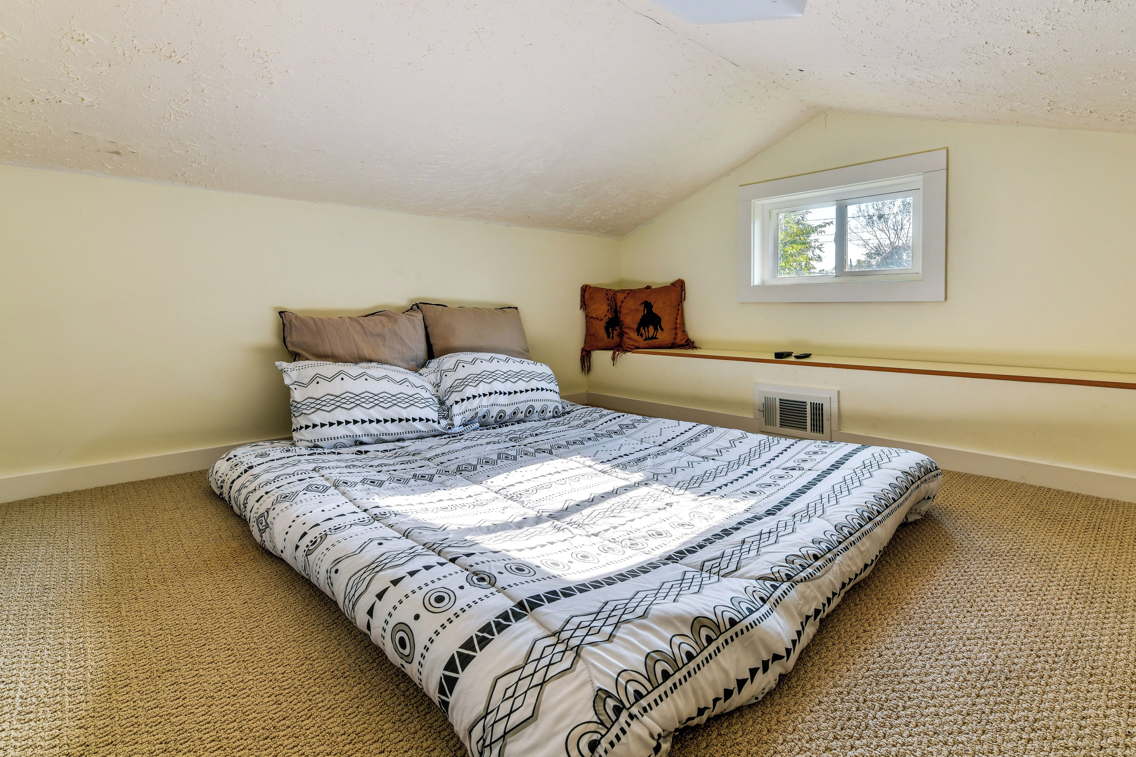A bedroom with a bed, a window, and a wall-mounted heater.