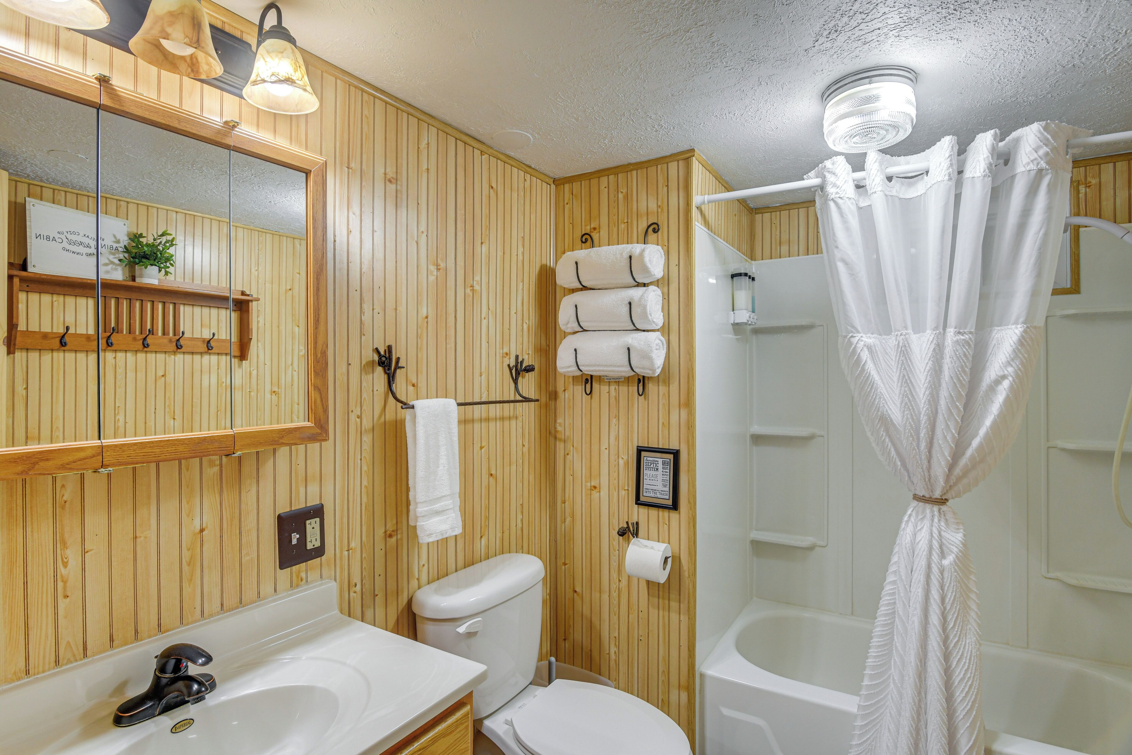 Une salle de bain aux murs lambrissés, équipée d’un lavabo, de toilettes et d’une baignoire.