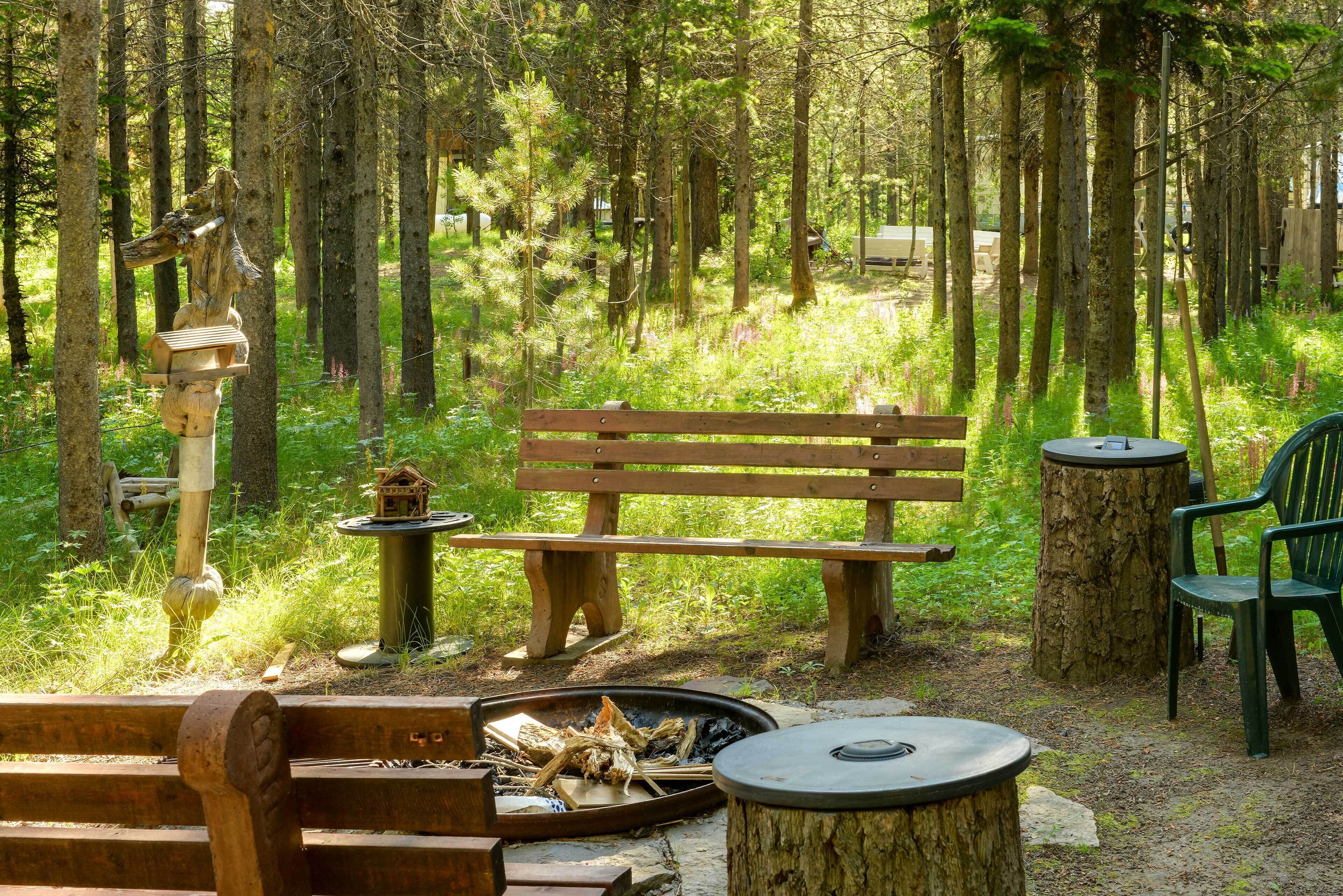 Un espacio de descanso al aire libre rústico con un banco de madera, un brasero y una mesa.