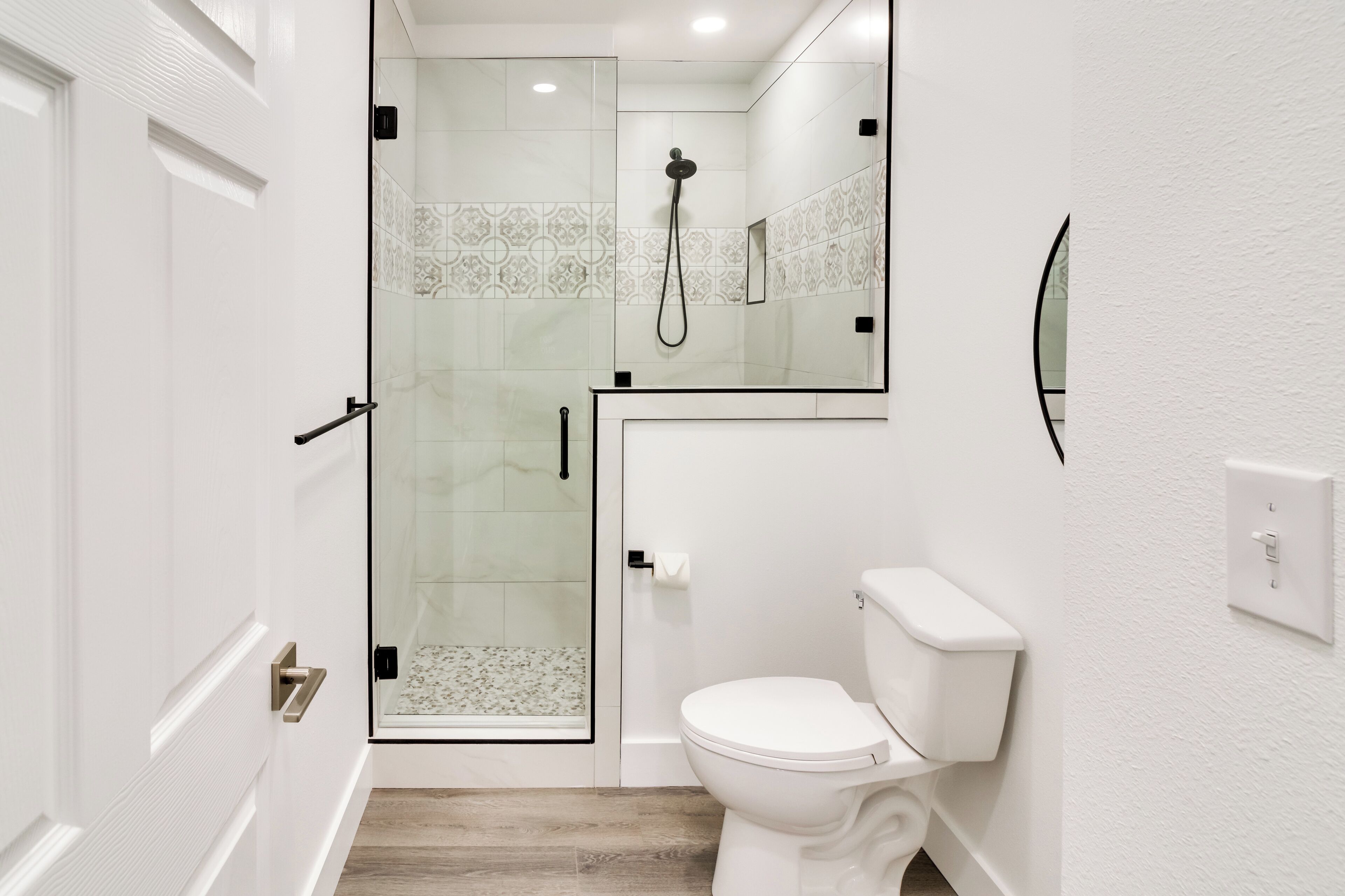 A modern bathroom with a glass-enclosed shower, a white toilet, and a tiled backsplash.