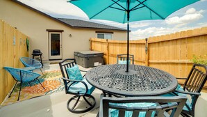 A patio with a round table, blue chairs, and a turquoise umbrella. - Newly Built Sparks Home w/ Hot Tub: 12 Mi to Reno! (Sparks)