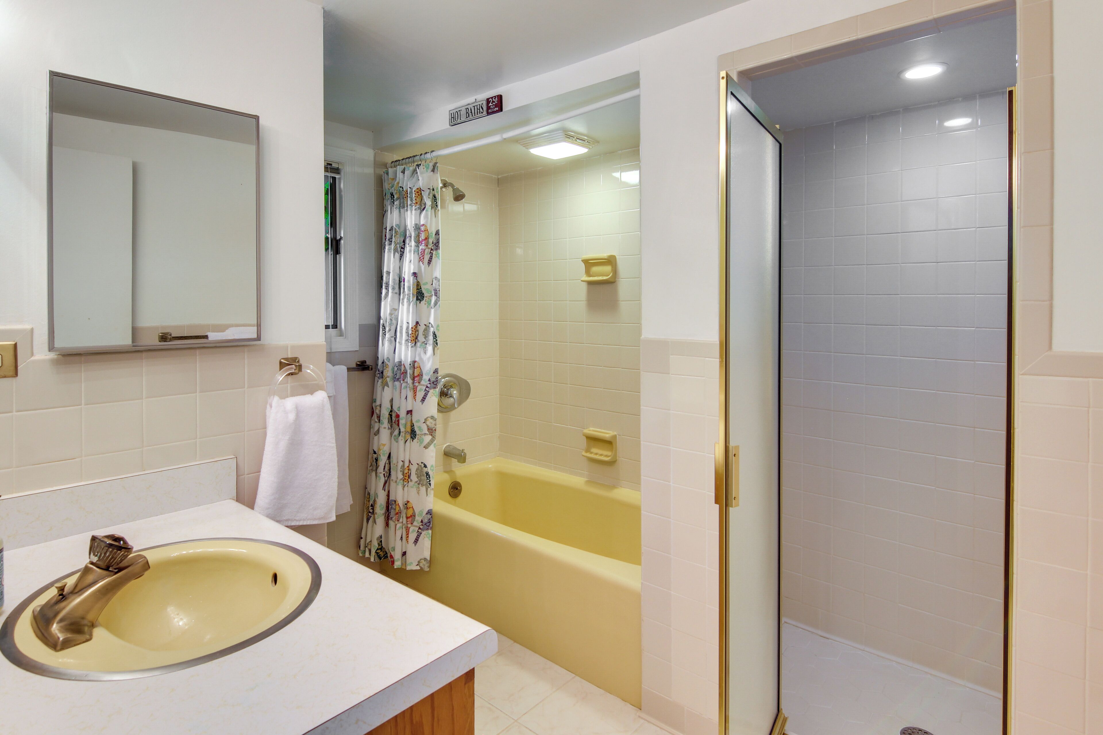 A bathroom with a sink, mirror, shower, and toilet.