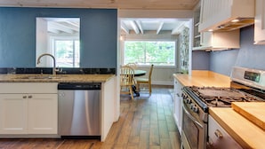 Une cuisine équipée d’un lave-vaisselle, d’une cuisinière et dotée d’un plancher en bois.