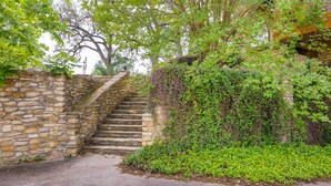 Una escalera de piedra que conduce a un edificio, rodeado de follaje y enredaderas.