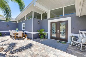 A covered patio with a dining table and chairs, a rocking chair, and a small garden area with plants. - Luxury St. Petersburg Home w/ Pool + Bay Access! (St. Petersburg)