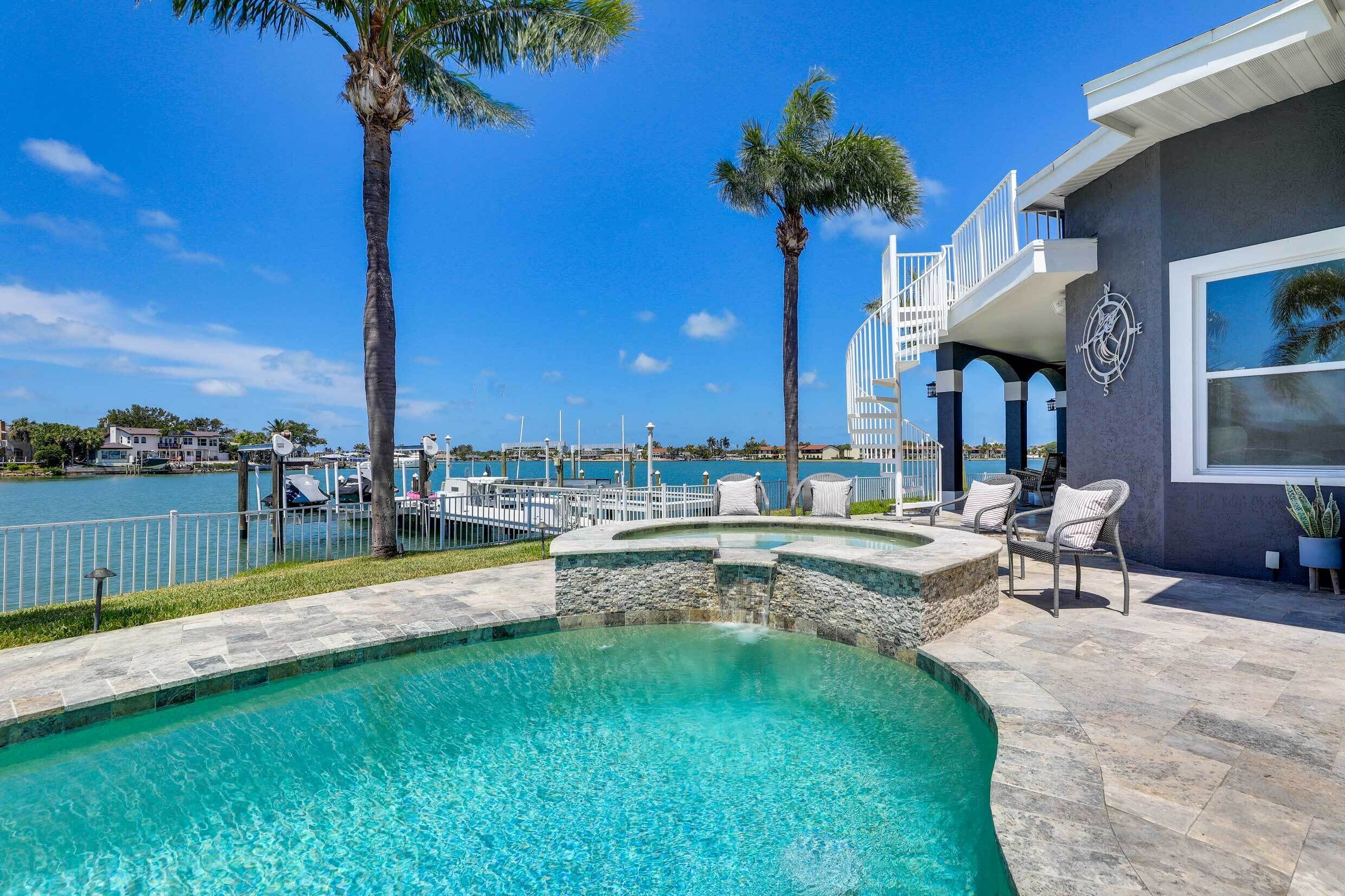 Une piscine avec vue sur le port de plaisance et une maison dotée d’un espace extérieur aménagé pour se détendre.