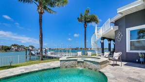 A swimming pool with a view of the marina and a house with outdoor seating.