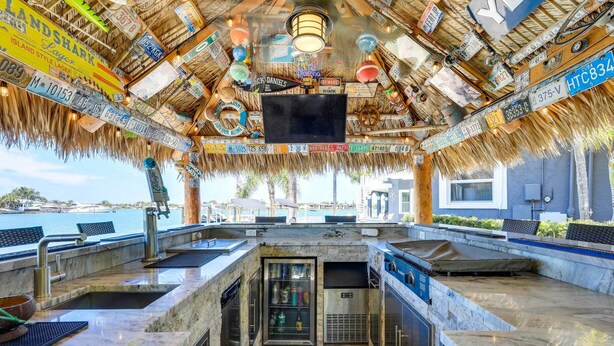 A bar area with a thatched roof, a large screen, and various signs and decorations.