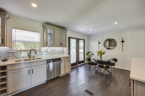 Een moderne keuken met een groot eiland, inbouwapparatuur en een eethoek met een tafel en stoelen.