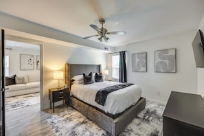 A modern bedroom with a bed, bedside tables, a ceiling fan, and artwork on the walls. - Modern Richmond Home w/ Deck, Close to Downtown! (Richmond)