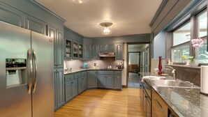 Een moderne keuken met lichtblauwe kastjes, een roestvrijstalen koelkast en een granieten aanrecht.