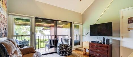 A living room with a sofa, a bean bag, a TV, and a ceiling fan.