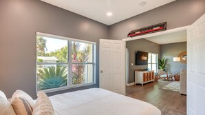 A bedroom with a large window, a bed, a white wardrobe, and a desk area with a chair. - Florida Gem: Saltwater Pool By Beaches & Kayaking! (Jensen Beach)