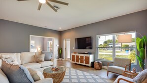 A modern living room with a sofa, armchairs, a coffee table, and a TV. - Florida Gem: Saltwater Pool By Beaches & Kayaking! (Jensen Beach)