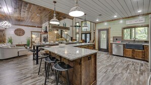 A spacious kitchen with a central island, wooden ceiling, and a stone accent wall. - Gorgeous Broken Bow Family Home w/ Private Hot Tub (Broken Bow)