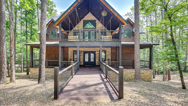 A lodge with a wooden exterior, a balcony, and a covered walkway leading to the entrance. - Gorgeous Broken Bow Family Home w/ Private Hot Tub (Broken Bow)