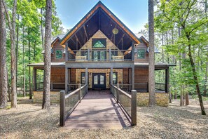 A lodge with a wooden exterior, a balcony, and a covered walkway leading to the entrance. - Gorgeous Broken Bow Family Home w/ Private Hot Tub (Broken Bow)