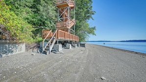 A wooden observation tower with a spiral staircase, located on a pebbly beach with a clear view of the water. - Private Beach at Waterfront Harstine Island Escape (Shelton)