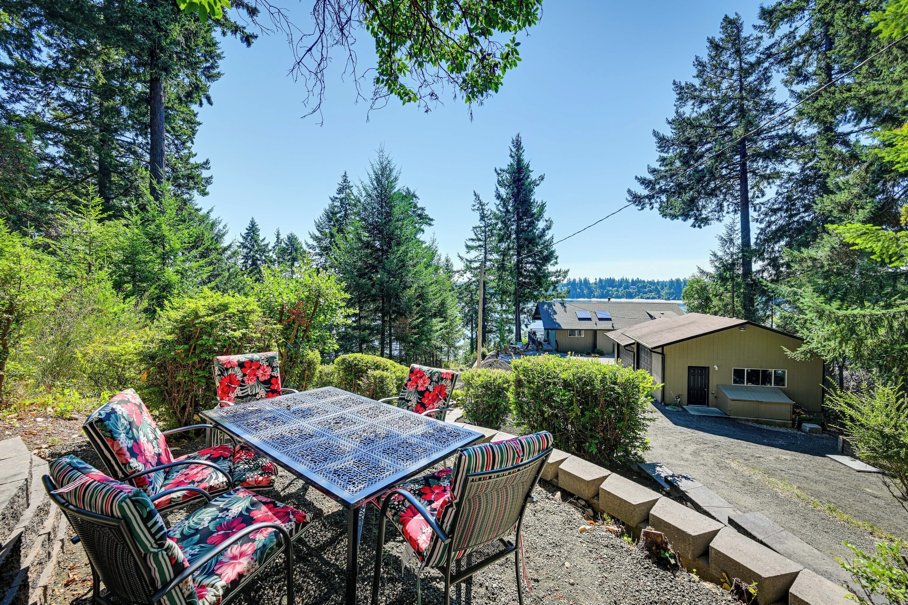 A patio with a table and chairs, surrounded by trees and a building in the background.