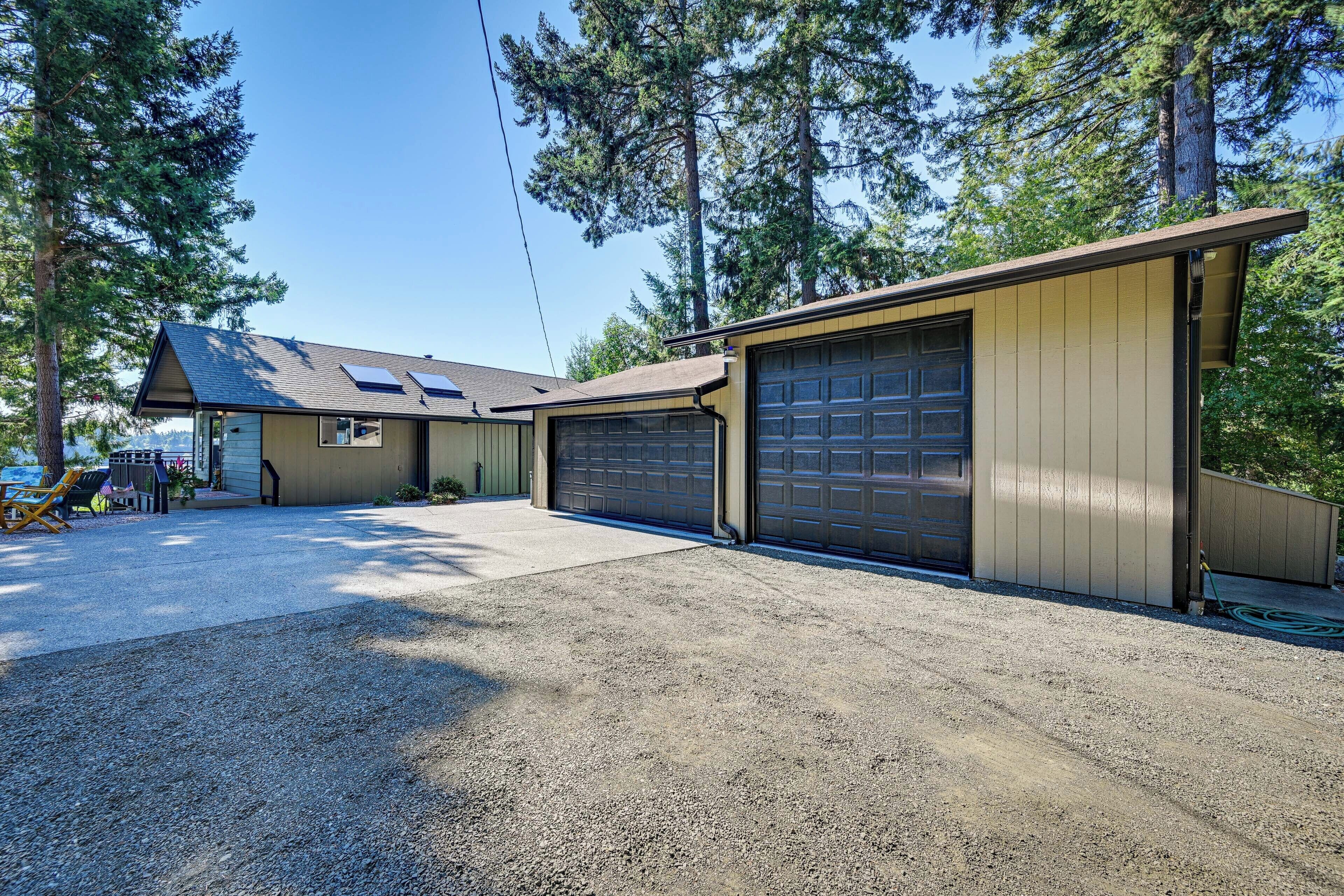 A two-story house with a garage, a covered patio, and a gravel driveway.