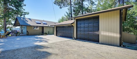 A two-story house with a garage, a covered patio, and a gravel driveway.