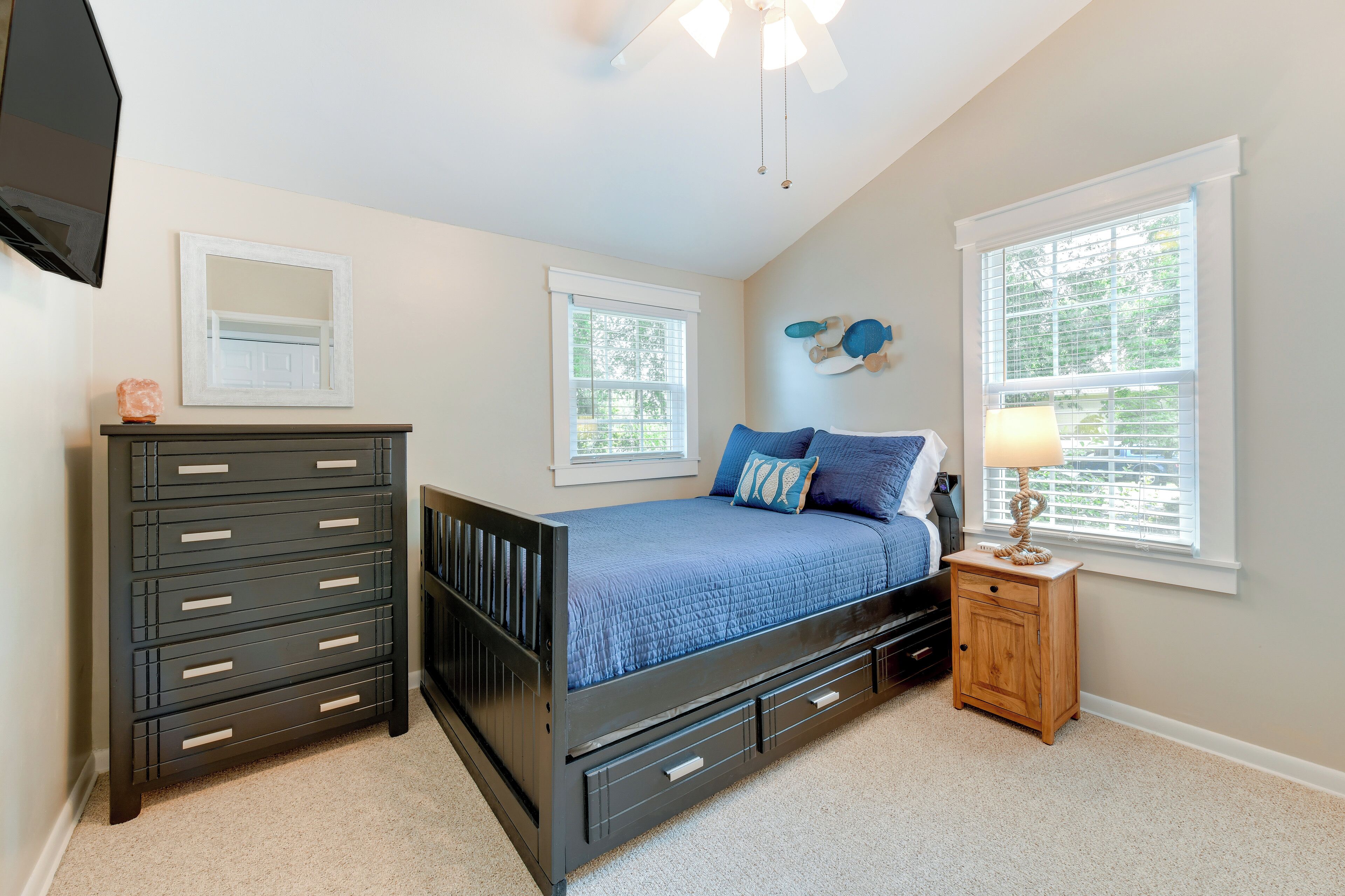 A bedroom with a bed, dresser, nightstand, and a ceiling fan.