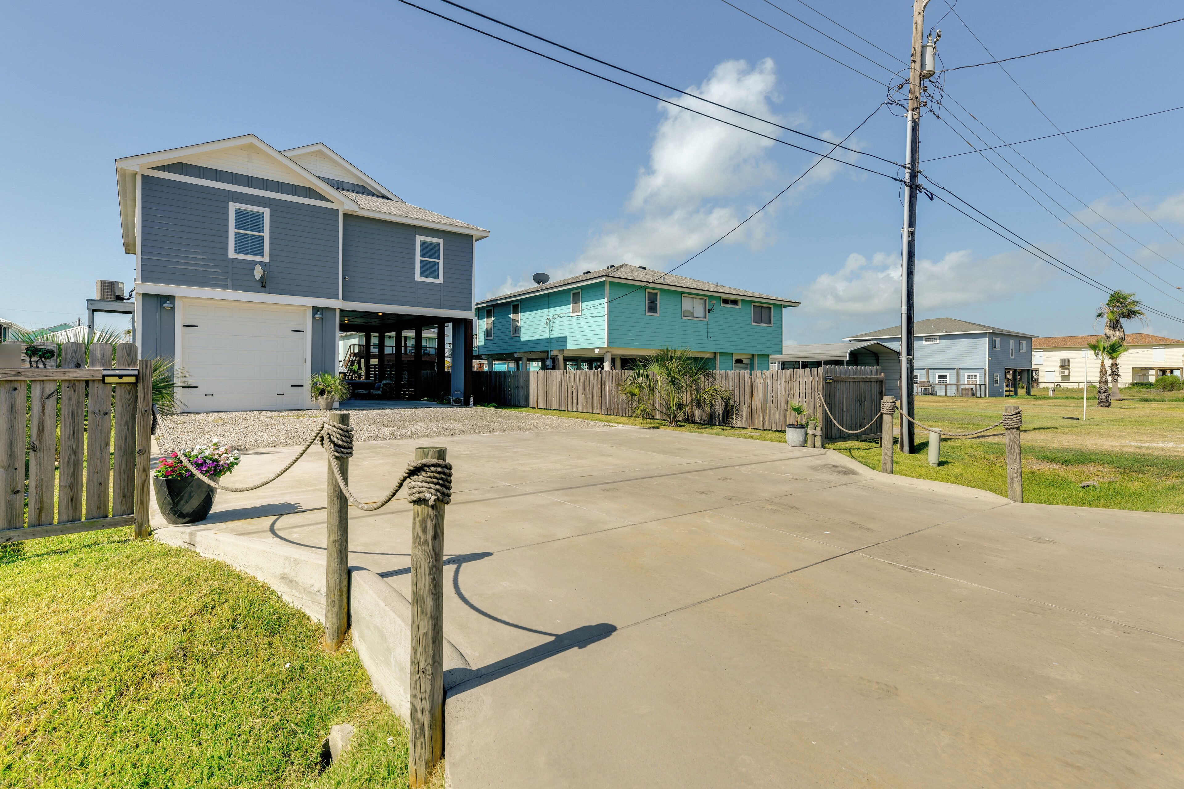 A residential area with houses, a concrete driveway, and a wooden fence.