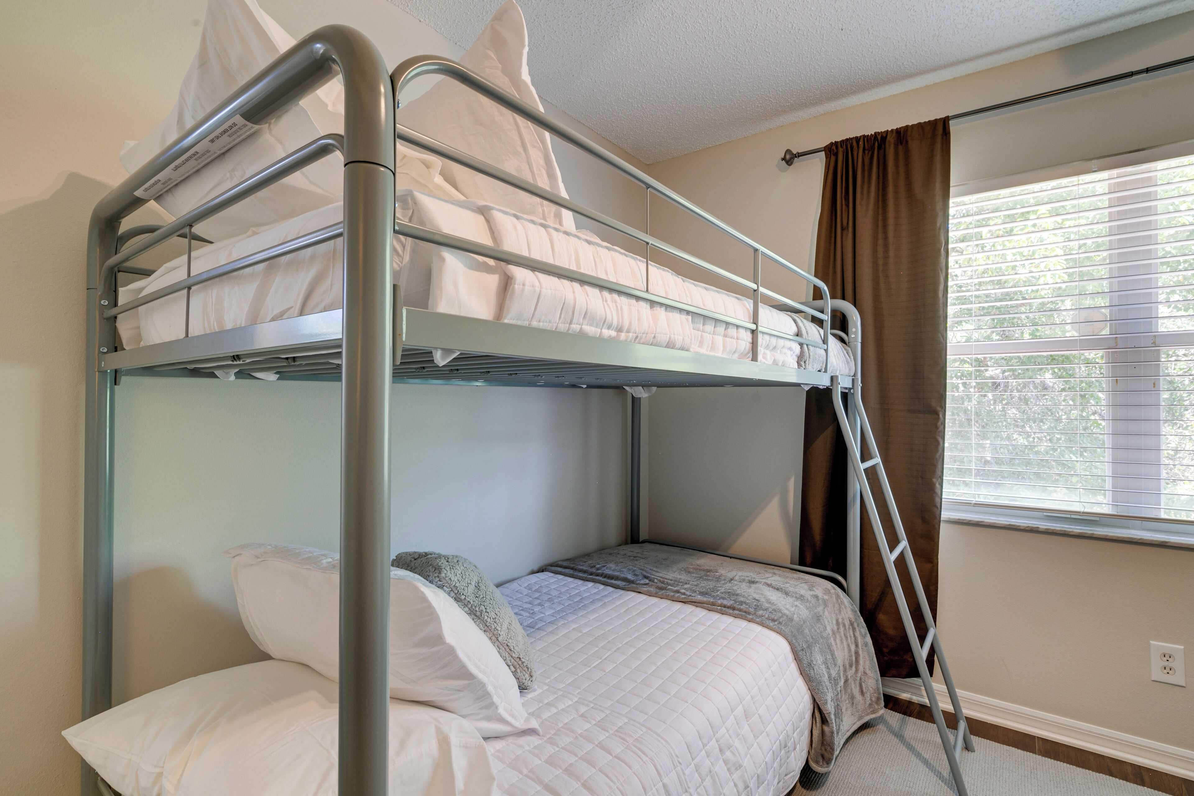 Ein Stockbett mit Metallgitter, einer Stehle und weißer Bettwäsche.