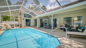 An indoor swimming pool with a glass ceiling, surrounded by outdoor seating and a patio area. - Spring Hill Home w/ Private Pool & Games! (Spring Hill)