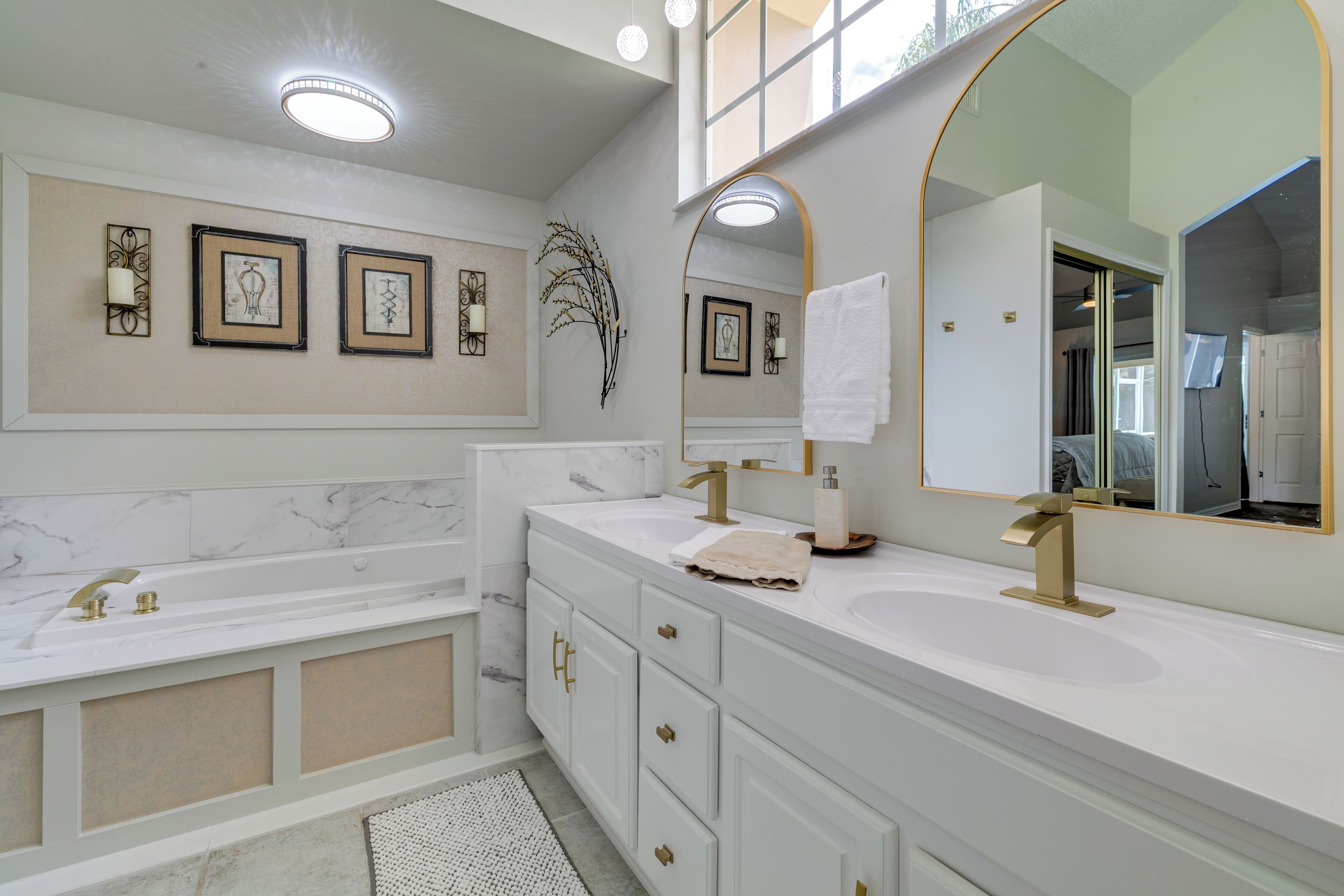 A modern bathroom with a large mirror, two sinks, a bathtub, and decorative wall art.