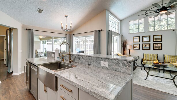 A modern kitchen with a large island, stainless steel appliances, and a dining area with a sofa and table. - Spring Hill Home w/ Private Pool & Games! (Spring Hill)