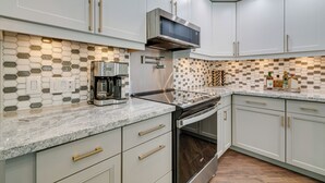 A modern kitchen with white cabinets, a stainless steel microwave, and a coffee maker. - Spring Hill Home w/ Private Pool & Games! (Spring Hill)
