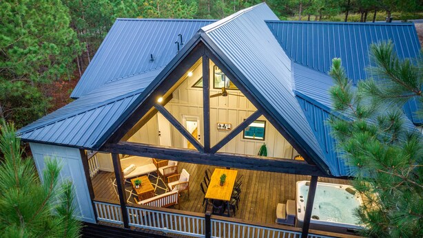 A cabin with a large deck, a hot tub, and a dining area. - 'painted Sky' Modern Broken Bow Cabin w/ Hot Tub! (Broken Bow)