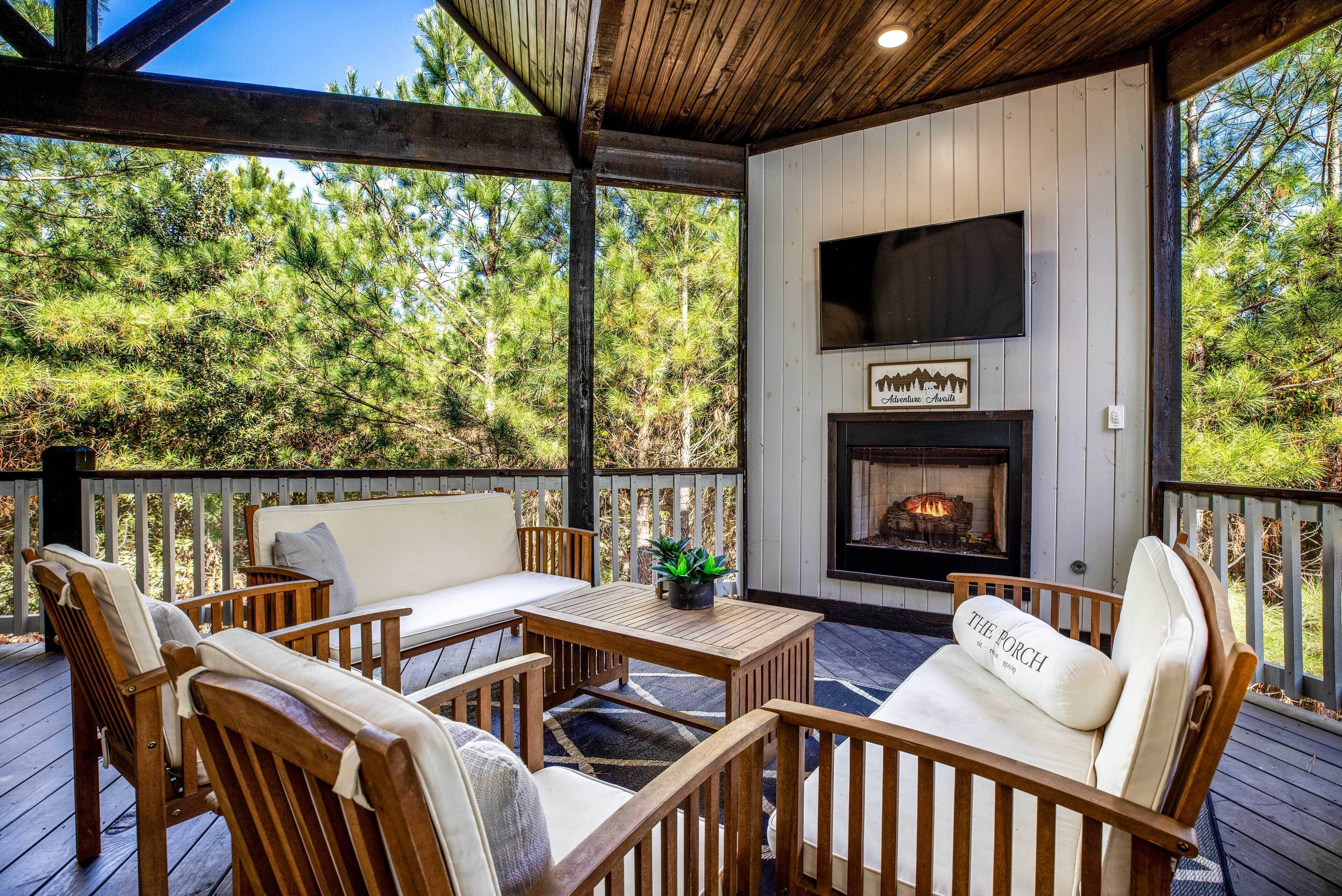 Una terraza de madera con mobiliario exterior, una chimenea y un televisor montado en la pared.