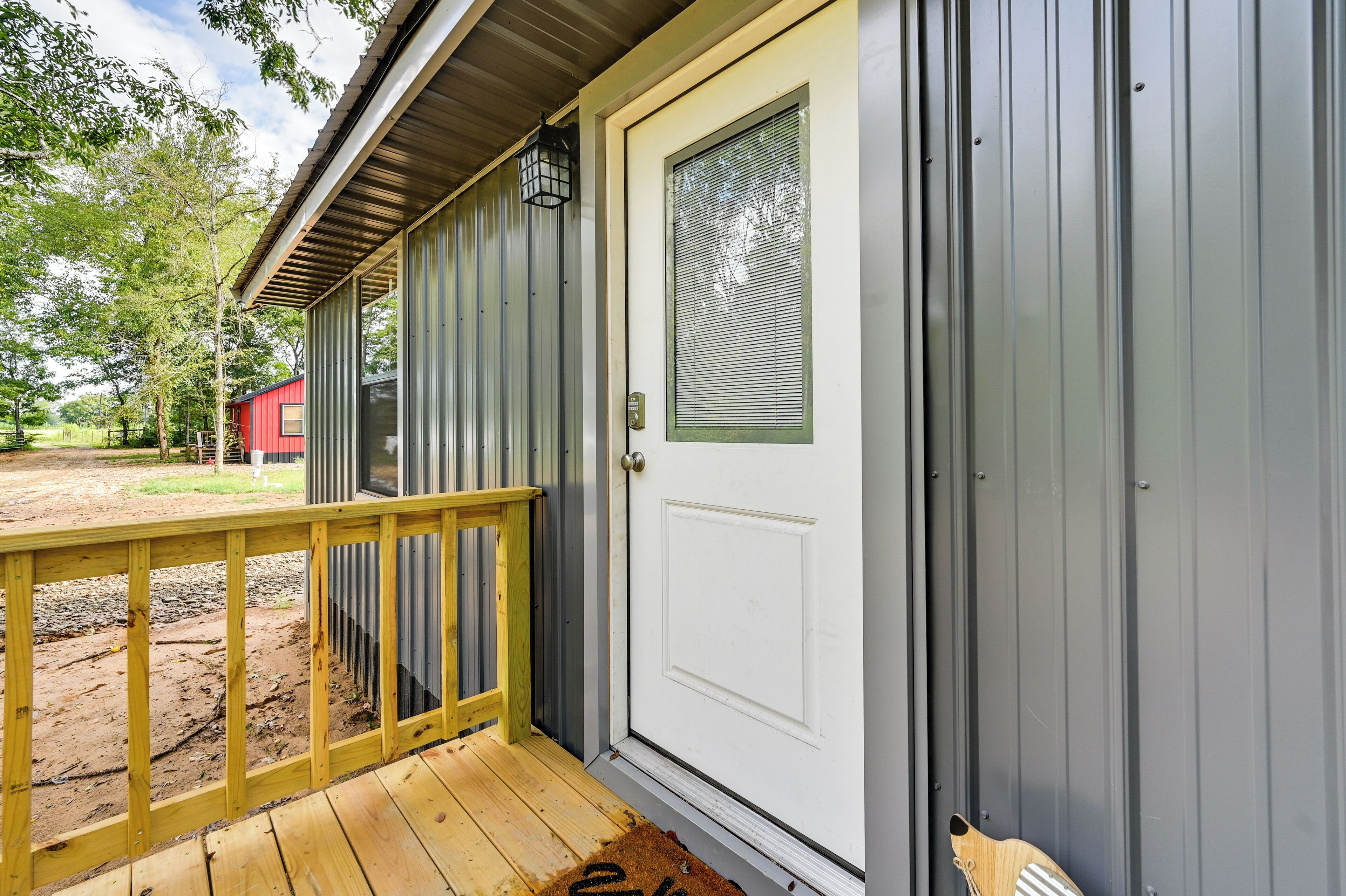 A wooden deck with a white door and a metal building.